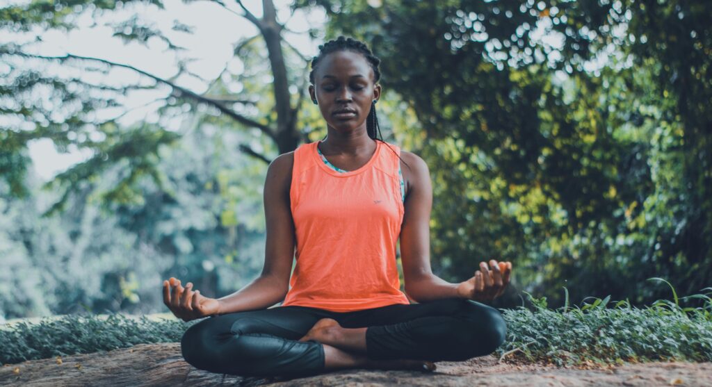  a woman practicing gentle morning yoga and meditation in a peaceful outdoor retreat setting.